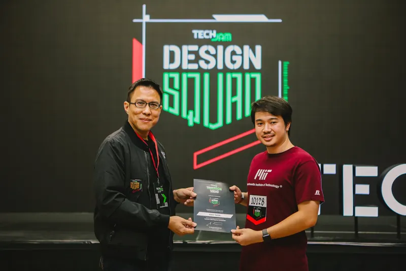 Arnon Tawong receiving a TechJam 2018 finalist award in front of the Design Squad backdrop